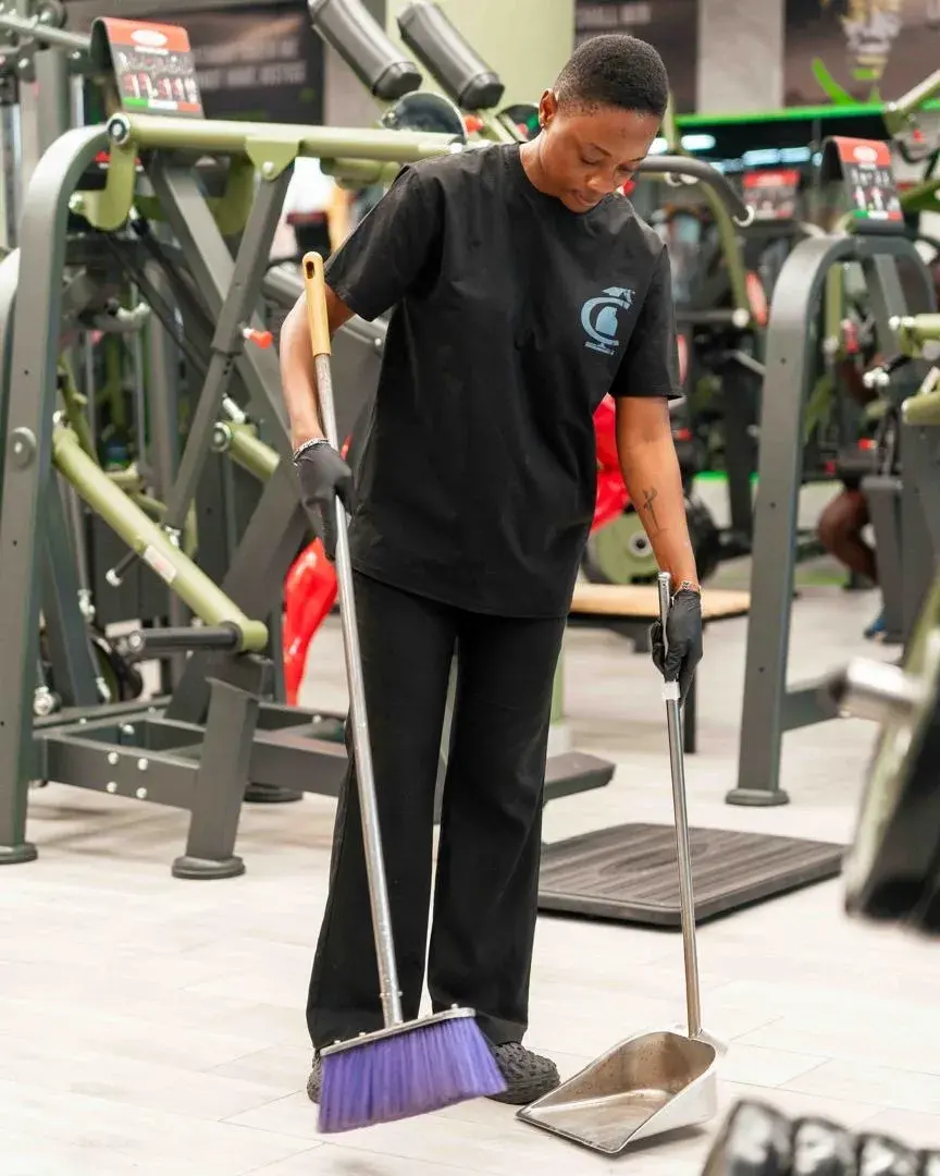 A Clean by AK cleaner sweeping the training floor between gym machines