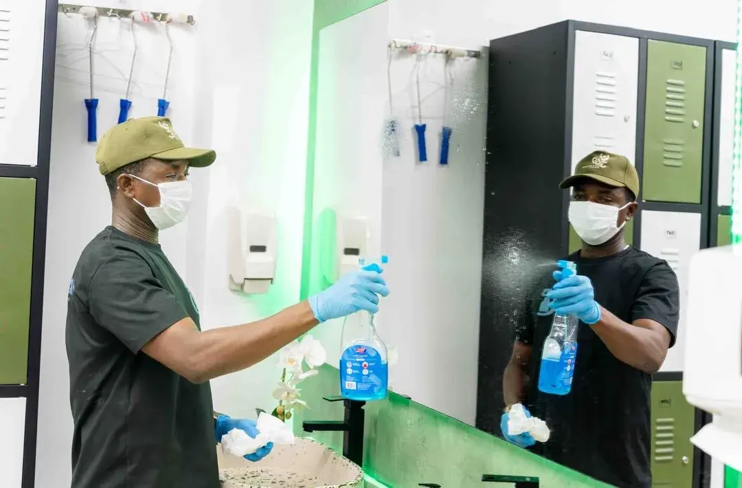 A Clean by AK team member carefully cleaning a washroom mirror