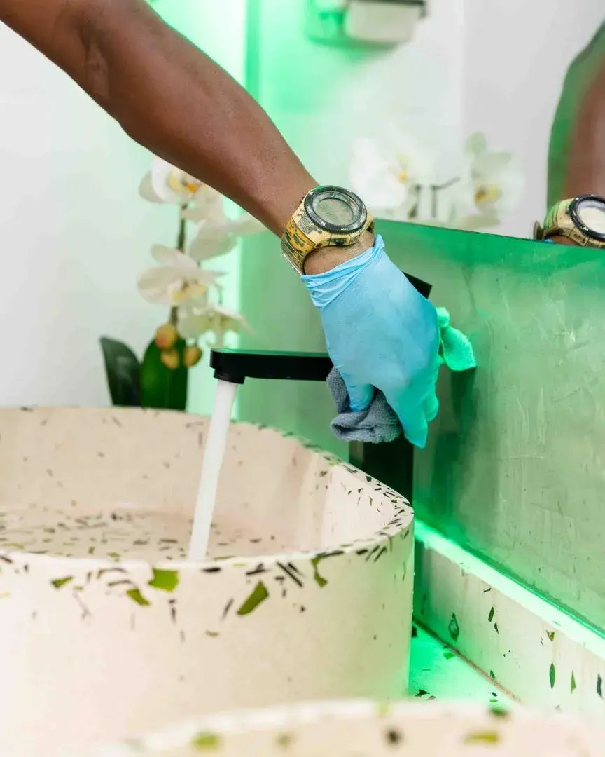A Clean by AK team member carefully polishing a tap with a microfibre cloth